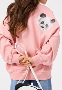 Pink sweatshirt with long sleeves, featuring a sequin panda design on the back. Displaying a relaxed fit and ribbed cuffs.