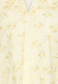 Robe jaune clair sans manches avec un petit imprimé floral orange pâle et une subtile texture à rayures verticales.