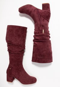 Bottes de pluie bordeaux en daim doux, au design décontracté, avec une fermeture éclair sur le côté et un talon carré pour plus de stabilité.