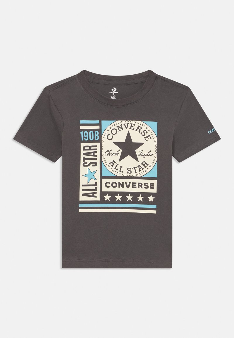 Koolgrijze T-shirt met korte mouwen met blauwe en crème Converse All Star logo, stergrafieken en de tekst "1908 Chuck Taylor" op de voorkant.