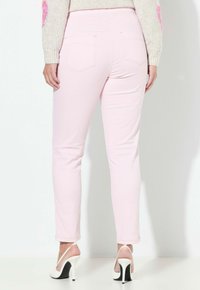 Vaaleanpunaiset kapeat farkut, joissa on sileä pinta, keskitason vyötärö ja takataskut. Yhdistetty valkoisiin korkokenkiin, joissa on musta yksityiskohta.