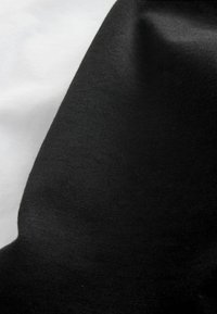 Kokvilnas audums ar melnu un balti dizainu; faktūras ir gludas un nedaudz elastīgas ar maigu matētu apdari.