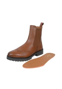 Brązowe skórzane botki Chelsea z detalami w stylu brogue, elastycznymi panelami bocznymi i gumową podeszwą. Zawierają wymienną wkładkę w kolorze brązowym.
