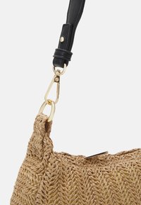 Włoska torba z tkanego siana z czarnym skórzanym uchwytem i złotymi elementami. Projekt obejmuje wzór w zygzak oraz gładkie zapięcie.