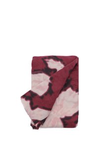 Tessuto a motivi rossi e rosa con una consistenza morbida, caratterizzato da un design tie-dye e bordi frangiati, ripiegato in forma rettangolare.
