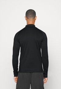 Langärmeliges schwarzes Sportshirt mit figurbetontem Schnitt, glatter Textur und ohne sichtbare Logos oder Muster. Hat einen hohen Kragen.