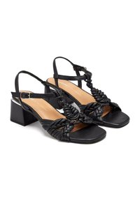 Sandalias de tacón negro con tiras trenzadas y diseño de punta cuadrada. Los tacones son gruesos para mayor estabilidad y comodidad.