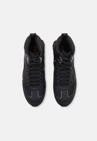 Zwarte sportieve schoenen met een bovenwerk van mesh en synthetisch materiaal, ronde neus en gevoerde kraag. Voorzien van veters, reflecterende accenten en een gestructureerde zool.