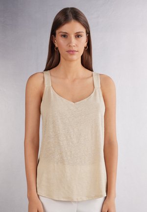 Lys beige tanktop med V-udskæring og brede skulderstropper. Fremstillet af blødt, struktureret stof med en afslappet pasform, der har en subtil glans.