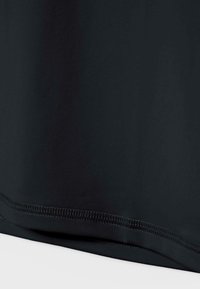 Nahaufnahme eines schwarzen Stoffes mit detaillierter Naht entlang des Saums auf einer glatten Textiloberfläche.