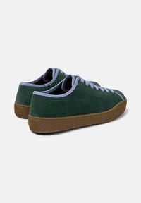 Zielone zamszowe sneakersy z jasnoniebieskimi sznurówkami i brązową gumową podeszwą, widziane z tyłu pod kątem.