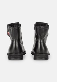 Black leather ankle boots with a textured back panel and side zipper. Chunky sole with a slight heel, simple design with no additional hardware.