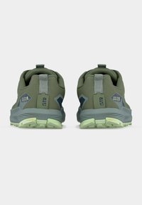 Ζευγάρι πράσινα παπούτσια πεζοπορίας με ανοιχτοπράσινες σόλες, λουράκια έλξης και ετικέτες «GTR» και «Lone Peak Gore-Tex» στις φτέρνες, ορατές από πίσω.