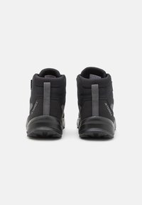 Black high-top outdoor shoes with a textured mesh upper and rubber sole; features a grey strap and logo on the side.
