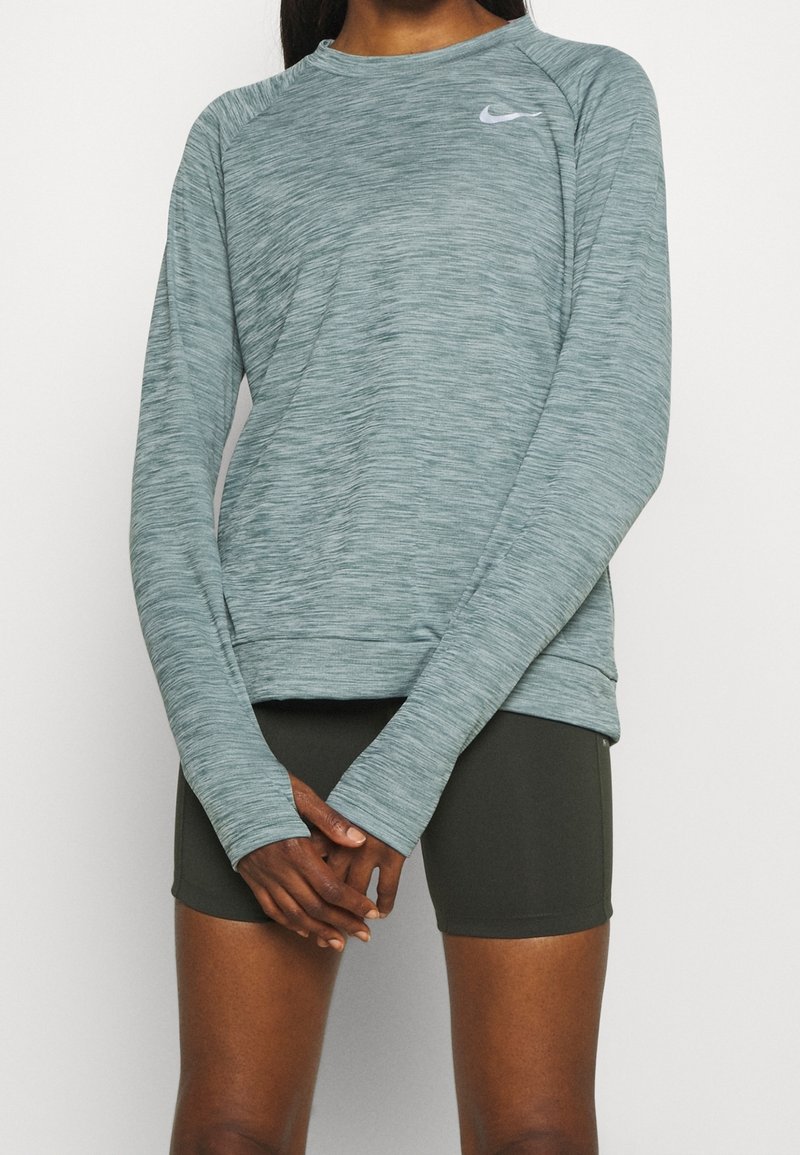 Helle teal langärmlige Sportoberteil mit melierter Textur, tailliertem Schnitt und einem kleinen grauen Nike-Logo auf der linken Brust.