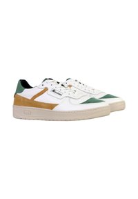 Baskets blanches avec des accents en suède vert et beige, semelle en caoutchouc texturée, fermeture à lacets et étiquette de marque sur le côté.