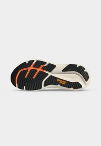 Semelle de chaussure de course avec un motif noir et orange, une base blanche et la marque "BROOKS GLYCERIN" sur un fond gris clair.
