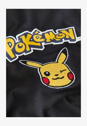 Črna tkanina z vezenim obrazom Pikachuja v rumenih in rdečih odtenkih, ob simbolu "Pokémon" v krepkem rumenem in modrem besedilu.
