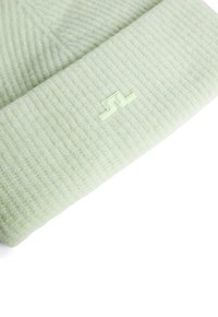 Vaaleanvihreä ribbimaista neulottua myssyä, jossa on käännetty reunus ja hieman vaaleammalla vihreällä brodeerattu logo. Pehmeä tekstuuri, lämmin materiaali.