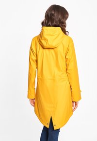 Impermeabile giallo con cappuccio, progettato con un orlo posteriore più lungo, texture liscia e dettagli con bottoni a pressione ai polsini e sul retro.