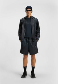 Black athletic outfit featuring a lightweight jacket, moisture-wicking shirt, elastic waistband shorts, and matching black sneakers.
