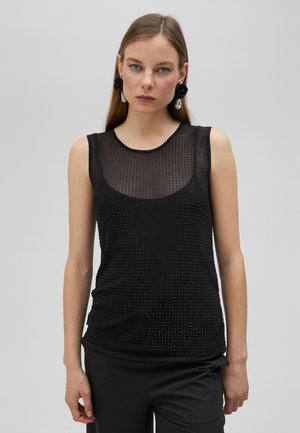 Black sleeveless top featuring a sheer mesh panel with textured dots, round neckline, and a fitted silhouette. Worn with sleek black trousers.