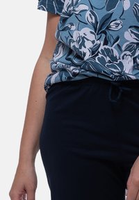 Top a fantasia floreale in tessuto di cotone blu e bianco abbinato a pantaloni con elastico blu navy dotati di cordoncino. Texture liscia, vestibilità rilassata.