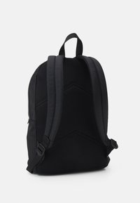 Czarny plecak z siateczkową teksturą na plecach i szelek, charakteryzujący się eleganckim designem oraz regulowanymi bocznymi klamrami dla dopasowania i wsparcia.