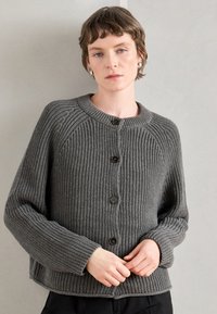 Γκρι πλεχτό cardigan με στρογγυλή λαιμόκοψη, μακριά μανίκια και καφέ κουμπιά. Διαθέτει ραβδωτή υφή και άνετη εφαρμογή.