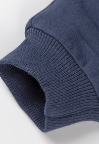 Ärmelbund aus dunkelblauem, weichem Strickstoff, mit gerippter Textur und glatter Oberfläche. Die Kanten des Ärmels sind sauber genäht.