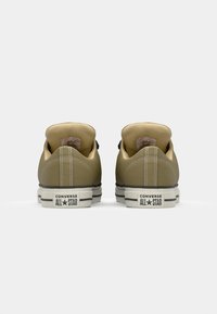 Khaki canvas sneakers with a low-top design, featuring a round toe, white midsole, and black rubber sole. Converse All Star branding on the heel.