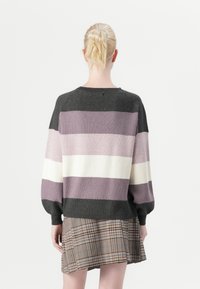 Oversized sweater in dark gray with horizontal stripes in light purple, pale pink, and white. Soft knit fabric with a rounded neckline.
