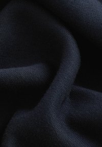 Material de culoare albastru închis, cu o textură netedă, având modele fine de tricot și o strălucire subtilă, drapat cu grijă pentru a evidenția astfel de calități precum moliciunea și flexibilitatea.