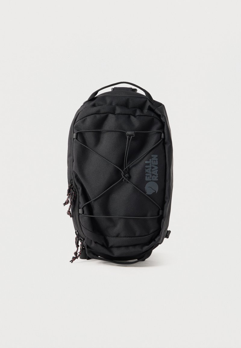 Μαύρο σακίδιο Fjällräven με μπροστινό ελαστικό κορδόνι, διπλό φερμουάρ και επάνω λαβή, εμφανίζεται πάνω σε απλό φωτεινό φόντο.