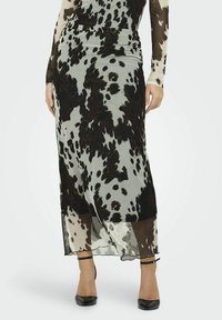 Langer, transparenter Rock mit einem schwarz und hellgrauen Tiermuster. Verfügt über eine enganliegende Taille und eine fließende Silhouette. Schwarze Schuhe mit Knöchelriemen.