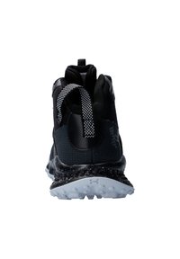 Zwarte sportieve schoen met een bovenwerk van mesh, een gestructureerde hak en een contrasterende witte gevlekte zool. Voorzien van een trekkabel en vetersysteem.