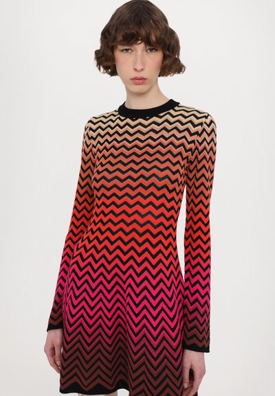 Vestido de mangas compridas com um padrão em zigzag em tons degradê de rosa, laranja e preto. Textura de malha, silhueta ajustada, decote redondo.