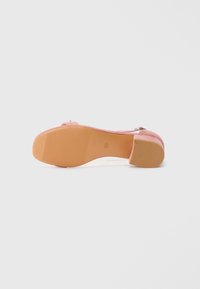 Rosa semsket høy heeled sko med rund tå, justerbar ankelreim og teksturert tan gummisåle. Minimal detaljering, glatt overflate.