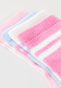 Bunte Socken in einem Stapel: pink gestreift, hellblau, weiß und pink Farbverlauf. Strukturierter Strickstoff, weiche Oberfläche und verschiedene Muster.