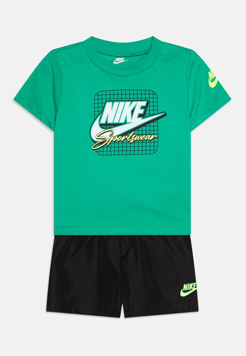 Green short-sleeve t-shirt with a black grid Nike logo; paired with black shorts featuring a small yellow-green Nike logo on the hem.