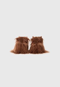 Bruna fuskpälsinlägg med en texturerad, shaggy yta, med runda former och små hornliknande detaljer på toppen.