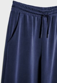 Námornícke modré tepláky z mäkkého materiálu, s elastickým pásom, šnúrkou a bočnými vreckami pre väčšie pohodlie.
