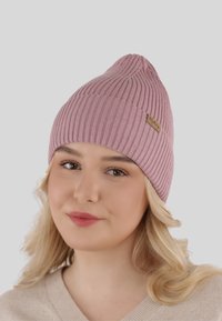 Pink ribbed knit beanie with a pointed top and a leather logo patch. Soft texture, fitted design, suitable for cold weather.
