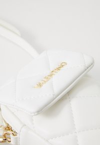 Λευκή τσάντα από καπιτονέ δέρμα με χρυσό λογότυπο "Valentino", που διαθέτει κλείσιμο με καπάκι και λεπτό λουρί. Λείος υφής και δομημένο σχήμα.