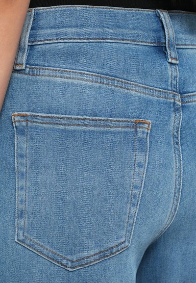 Lyseblå denimjeans med en tætsiddende design, der har to baglommer og synlige sydetaljer i en kontrasterende orange farve.
