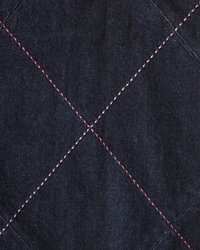 Tamni traper tkanina s dijamantnim uzorkom, šivena kontrastnom ružičastom niti, naglašavajući strukturiranu površinu i precizno šivanje.