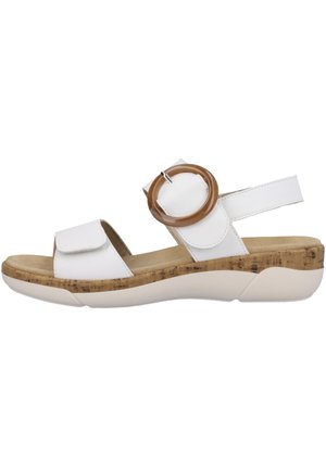 Witte sandaal met een platte kurken en rubberen zool, twee verstelbare banden en een ronde bruine accentdetail aan de zijkant.