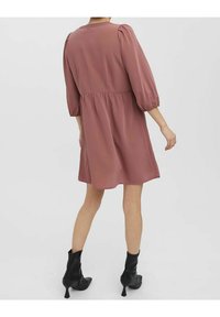 Roze korte jurk met een getailleerde taille, pofmouwen en een ronde halslijn. Draag het met zwarte enkellaarsjes met een spitse neus.