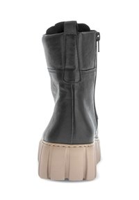 Black leather ankle boot with beige thick ridged sole, rear pull tab, and side zipper, shown from back view.