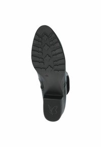 Czarna podeszwa buta z teksturowanym bieżnikiem, z blokowym obcasem i logo w kształcie motyla. Gładkie wykończenie bez widocznych elementów hardware czy akcentów.